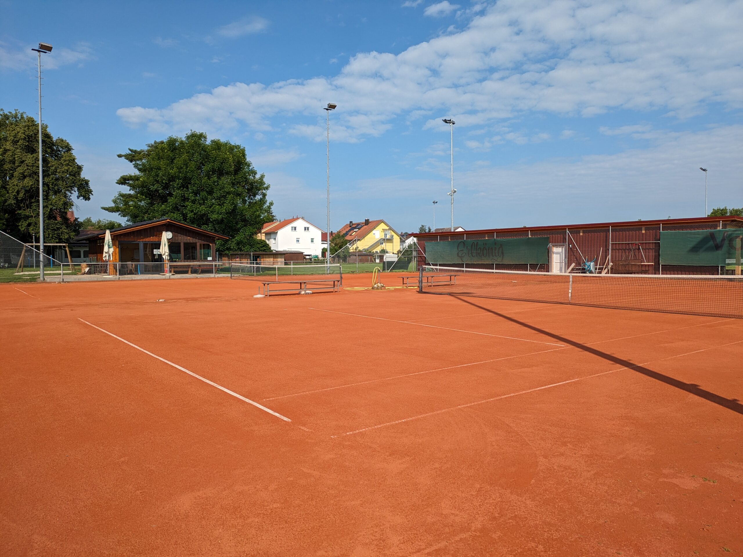 Sportplatz mit Tennisnetz, im Hintergrund Familienhäuser und Tennishäusl